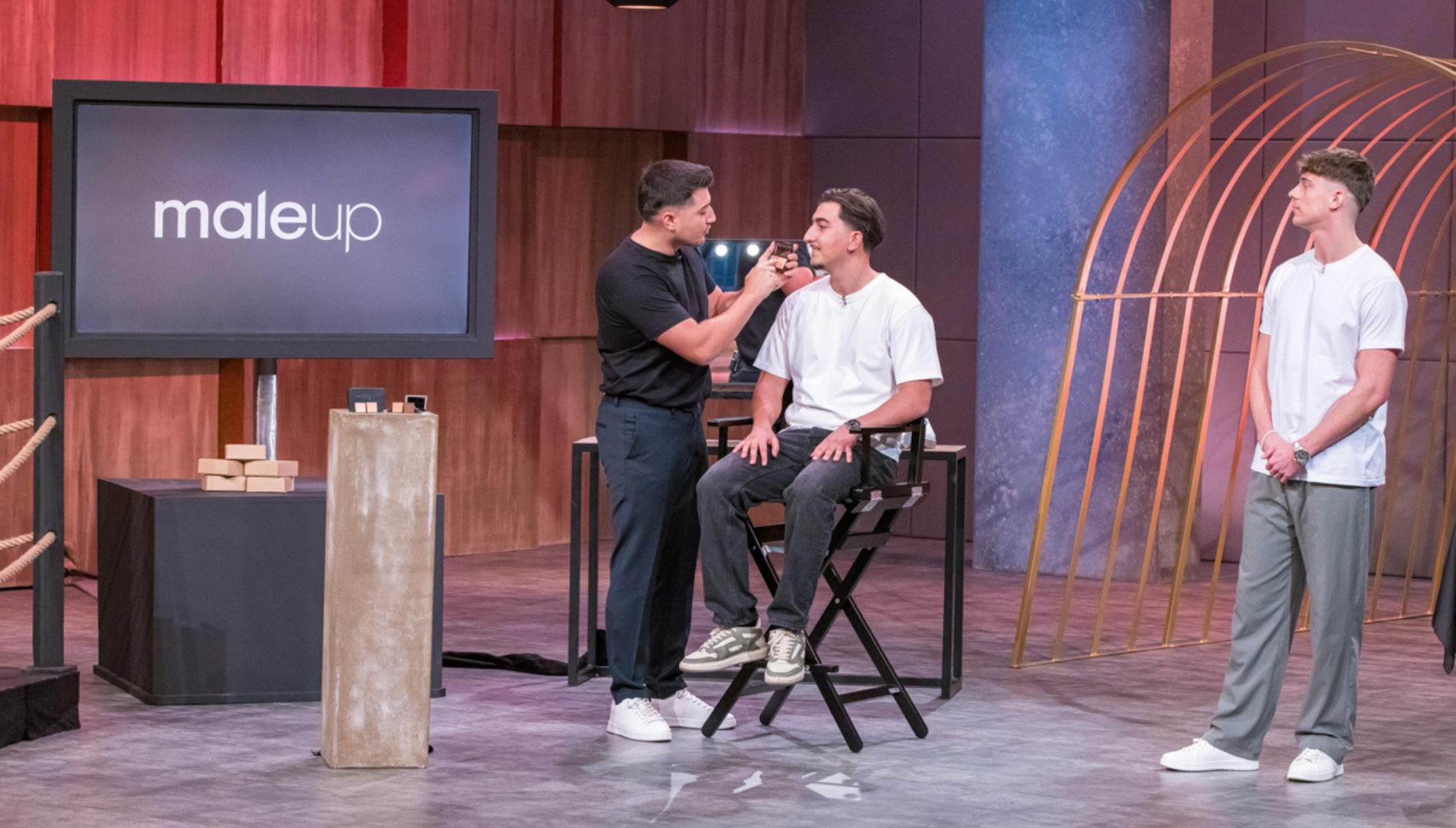 Präsentation von MaleUp in der TV-Show „Die Höhle der Löwen“ – Gründer demonstriert die Anwendung des Concealers auf einem Model, während ein weiterer Teammitglied auf der Bühne steht. Im Hintergrund ist das MaleUp-Logo auf einem Bildschirm zu sehen